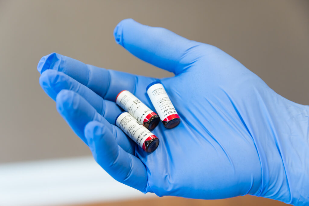 A provider's hand in a blue glove holds out pellets for hormone optimization therapy, which we can pair with weight reducing medicine in Reno for optimal results.