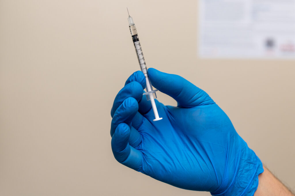 A provider's hand wearing a blue glove holds up a syringe with weight-reducing medicine in Reno.