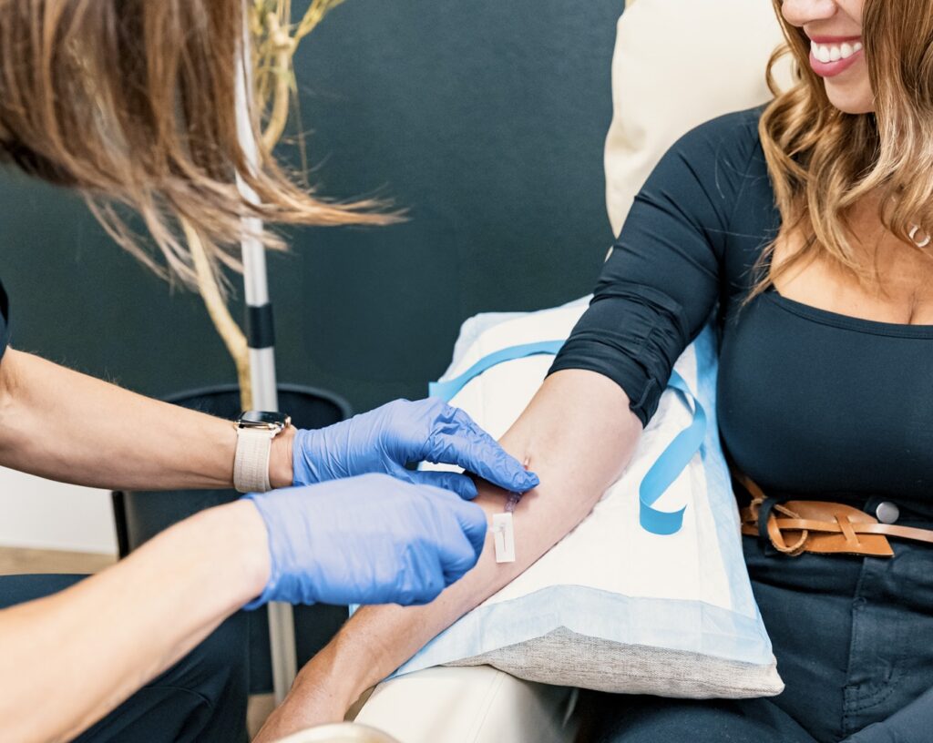 A smiling woman gets an IV infusion in Reno from one of our expert providers as she sits in a comfortable lounge chair.